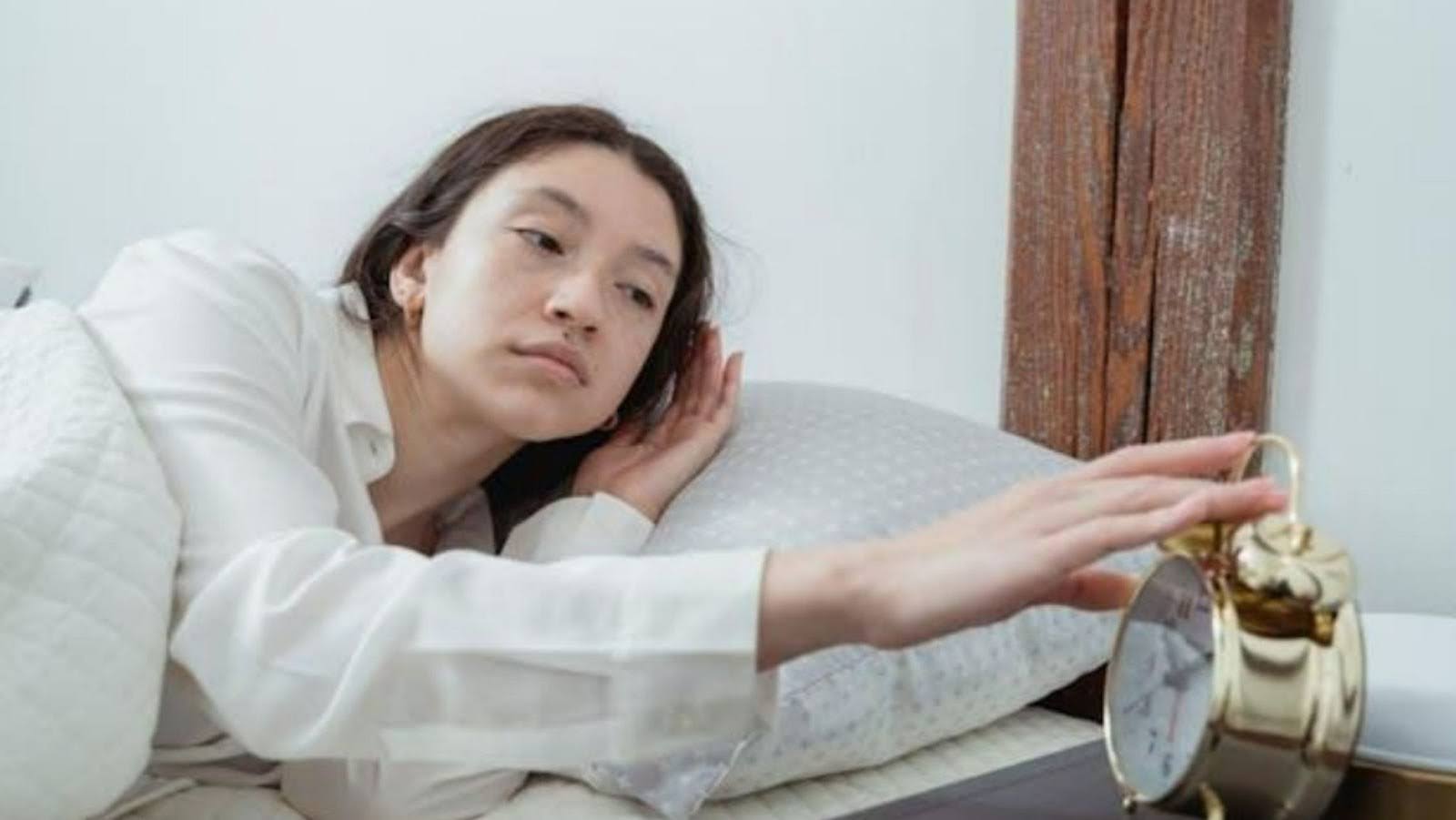 A woman wearing a sleeping mask, lying on her back in bed
