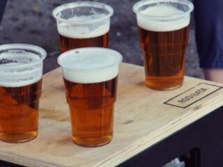 Four plastic glasses with beer, on a wooden table or chair.
